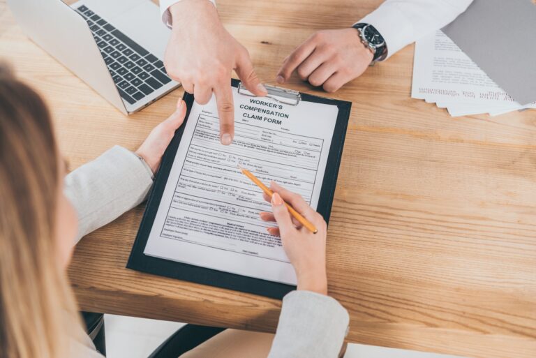 cropped view of businessman pointing with finger at compensation claim form while woman holding