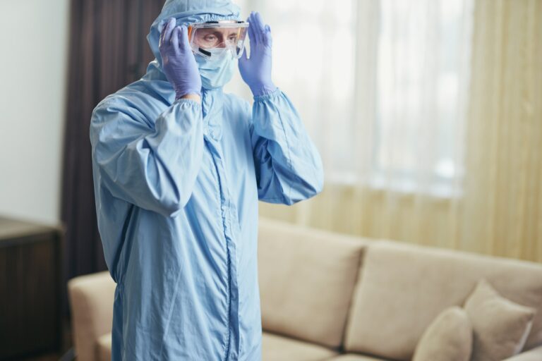 Man wearing safety glasses while disinfecting teh hotel room